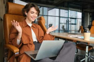 Portrait of surprised woman looks amazed at laptop screen, reacts to wonderful news brought up